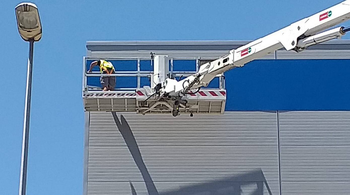 Instalación en altura de rótulo de PVC sobre fachada acristalada